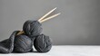 Dark yarn balls and knitting needles on gray.
