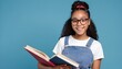 © Fabian - Young smiling smart nerd african american girl teen student wear denim clothes holding books prepare for exam notebook isolated on blue background Education in high school university college concept.