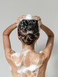 back view of young woman washing wet and foamy hair isolated on grey