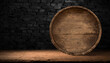 A brown hardwood barrel rests on a wooden table against a brick wall, blending in with the landscape in its tints and shades, illuminated by the darkness around