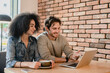 © InsideCreativeHouse - Young happy multiethnic multicultural couple using laptop in cafeteria, watching series, working together online on projects startup, doing homework, preparing for exams in restaurant