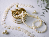 Fototapeta Paryż - Mother-of-pearl gold box with pearl jewelry on a white table.
