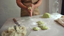 Details On Hands Of A Young Woman Chef, Housewife In Beige Apron, Cutting Green Spinach Dough, Making Sausage And Rolling Out Dough, Preparing Dumpling In The Rustic Interior Of A Rural House Kitchen