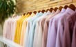 A row of boldly colored shirts hangs in perfect choreography on a white wall