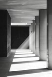 Fototapeta Natura - A monochromatic image showcasing a lengthy hallway with stark contrasts and repeating elements stretching into the distance