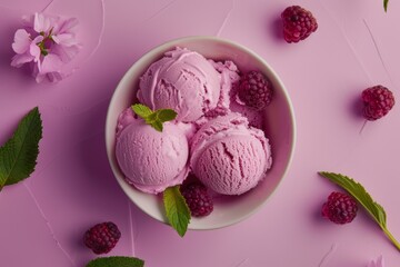 top view of a bowl of ice cream balls with raspberries in pink background