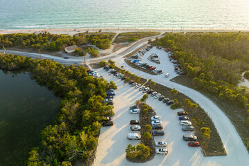 Wall Mural - Vehicle parking area with cars parked on ocean beach parking lot at sunset. Summer vacation on beachfront in Southern Florida