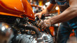 Detail-oriented mechanic's hands conduct a precise oil check on an eye-catching orange motorcycle, highlighting the contrast between grease and vivid color