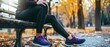 © SKIMP Art - A woman in black leggings and purple sneakers is sitting on a bench, holding her leg with one hand as she shows pain after running or doing sports Generative AI