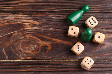 Wall Mural - Many dices and green game pieces on wooden table, flat lay. Space for text