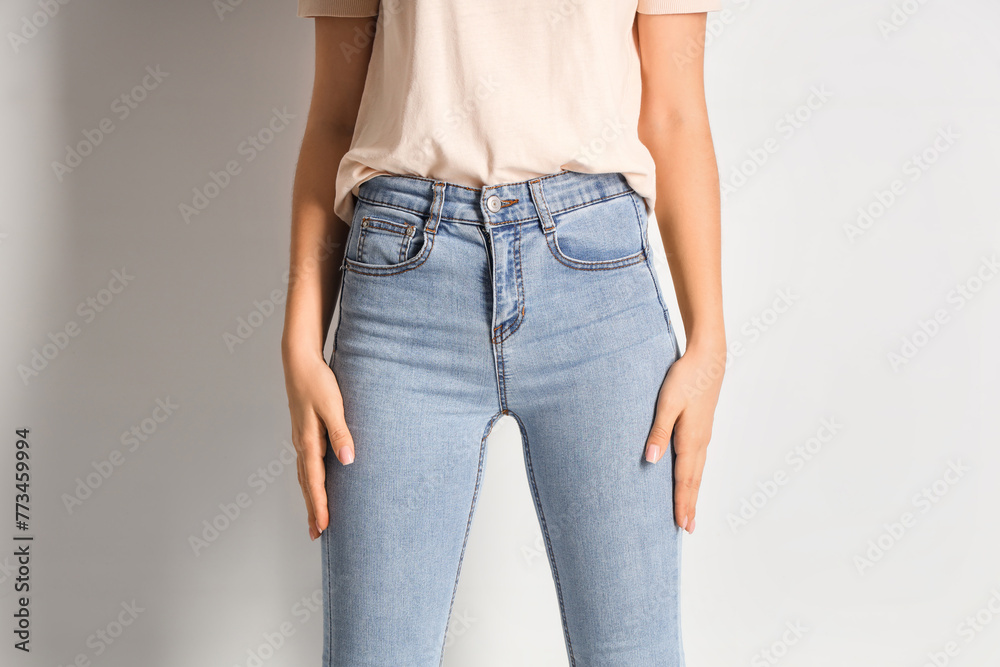 Young woman in stylish jeans pants on white background