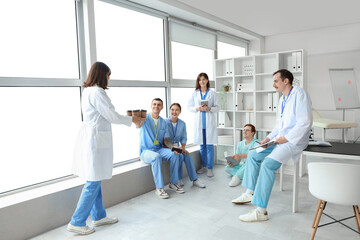 Wall Mural - Female doctor bringing coffee to her colleagues in clinic