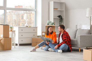 Wall Mural - Happy young couple reading interior design magazine in room on moving day