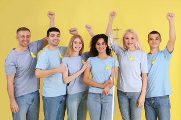 Canvas Print - Young woman undergoing chemical therapy course and people with yellow awareness ribbons on color background. World Cancer Day