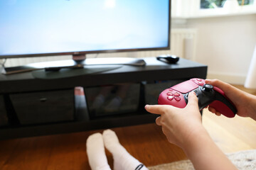 Child playing video games with controller at home, closeup