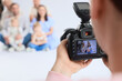 © Pixel-Shot - Male photographer taking picture of big family in studio, closeup