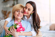 Tender hugs. Happy mature woman with flowers enjoying in daughter's affection on Mother's day. Birthday, Mothers day, women's day, retired, family, relation, motherhood.
