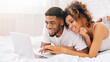 © Prostock-studio - Couple enjoying content on a laptop in bed