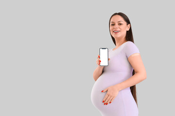 Wall Mural - Young pregnant woman with medical patch and mobile phone after vaccination on light background