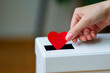 Female hand putting a red paper heart into a slot of white donation box. Charity, donation, election, fund raising, help, love, gratitude concept