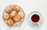 Fototapeta Na sufit - Round-shaped pastry, sprinkled with powdered sugar, on a plate and a cup of tea. view from above