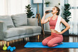 © Summit Art Creations - Athletic and sporty woman drinking water on fitness mat after finishing home body workout exercise session for fit physique and healthy sport lifestyle at home. Gaiety home exercise workout training.
