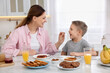 © New Africa - Mother and her cute little son having breakfast at table in kitchen