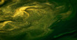 Glitter fluid texture. Shiny ink drip. Defocused green yellow color metallic golden sparkle grain particles acrylic paint liquid emulsion flow abstract art background.