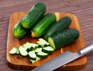 Wall Mural - Ripe juicy cucumbers on a wooden table closeup