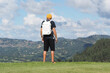 Man with white backpack looking at mountains. Rear shot.