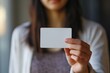 A cute girl holds a white card in front of her. bank card close-up