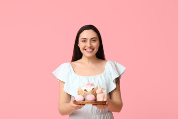 Sticker - Beautiful young woman with sweet Easter cake, eggs and toy bunny on pink background