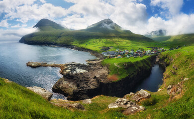 Wall Mural - Village of Gjogv on Faroe Islands with colourful houses. Mountain landscape with ocean coast