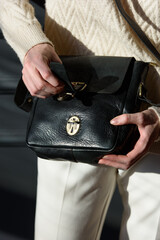 Poster - Studio portrait of woman holding black leather bag, posing on gray background.