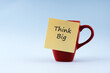 Think big text on adhesive note stick on a coffee cup