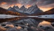 Tranquil mountain lake landscape with snow capped mountain peaks reflecting in the water at sunrise