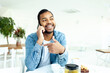 cheerful african american man with braces talking on the phone in a white cafe, a man in a denim shirt smiles and communicates on a mobile phone in a restaurant