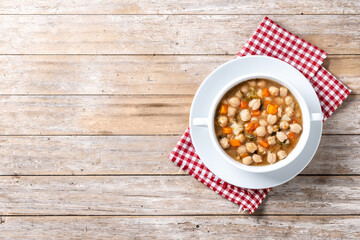 Wall Mural - Chickpeas soup with vegetables in bowl on wooden table. Top view. Copy space