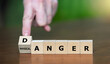 Hand turns wooden cube and changes the expression 'physical anger' to 'danger'.
