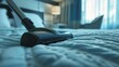 A vacuum moves over a bed in a close-up shot, capturing the intersection of domestic cleaning and hotel tidiness practices