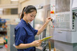 Engineer women control operate CNC industrial machine in metal production workshop. Asian young female industry worker.