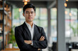 © koala studio - A man in a formal suit standing confidently with his arms crossed
