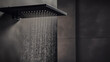 Zoom sur un pommeau de douche allumé, dans une douche au carrelage gris anthracite. Eau chaude qui coule, jet, goutte d'eau, buée. Salle de bain, salle d'eau. Architecture moderne et contemporain. 