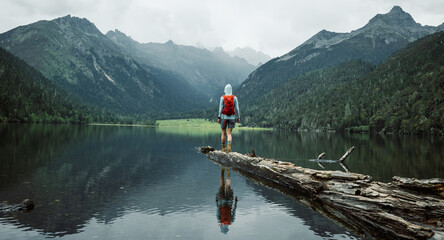 Wall Mural - Hiking woman on a one plank bridge in high altitude mountains