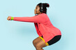 Woman in sportswear squatting with yellow fitness band, showcasing a healthy lifestyle and workout motivation.