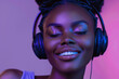 A black girl wearing headphones, eyes closed, enjoying music from her phone in front of a purple backdrop