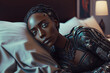 A black, African-American, dark-skinned female robot lies in bed in the bedroom. 
