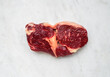 Raw beef steak on white marble background, top view