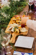 © ADDICTIVE STOCK - Anonymous guest reaches for a selection from a bountiful cheese platter amidst a floral banquet, with glasses of wine and cheerful ambiance
