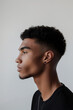 Side profile view of a young man sporting a stylish tapered fade haircut against a neutral background